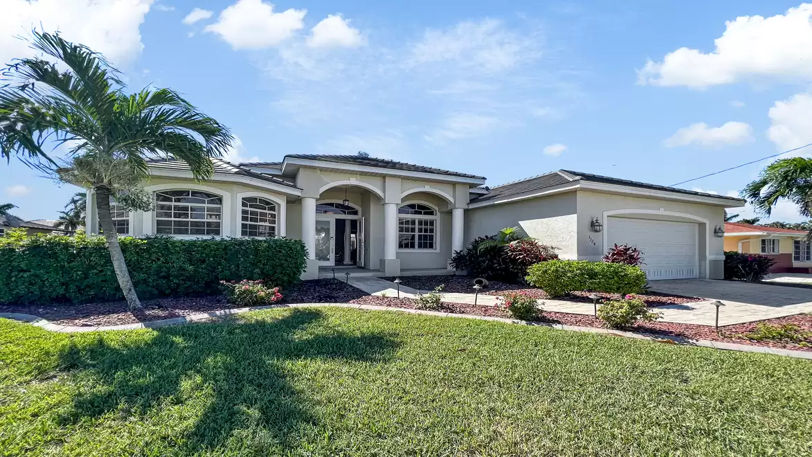 Villa Boaters Dream - Spacious single-family home with palm tree, manicured garden, and blooming bushes under a bright blue sky.