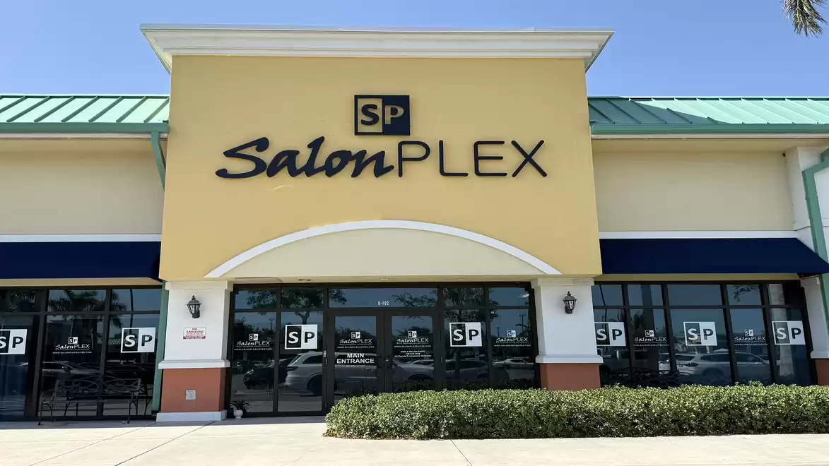 Front view of a shop with a yellow facade and the sign 'Salon PLEX'.