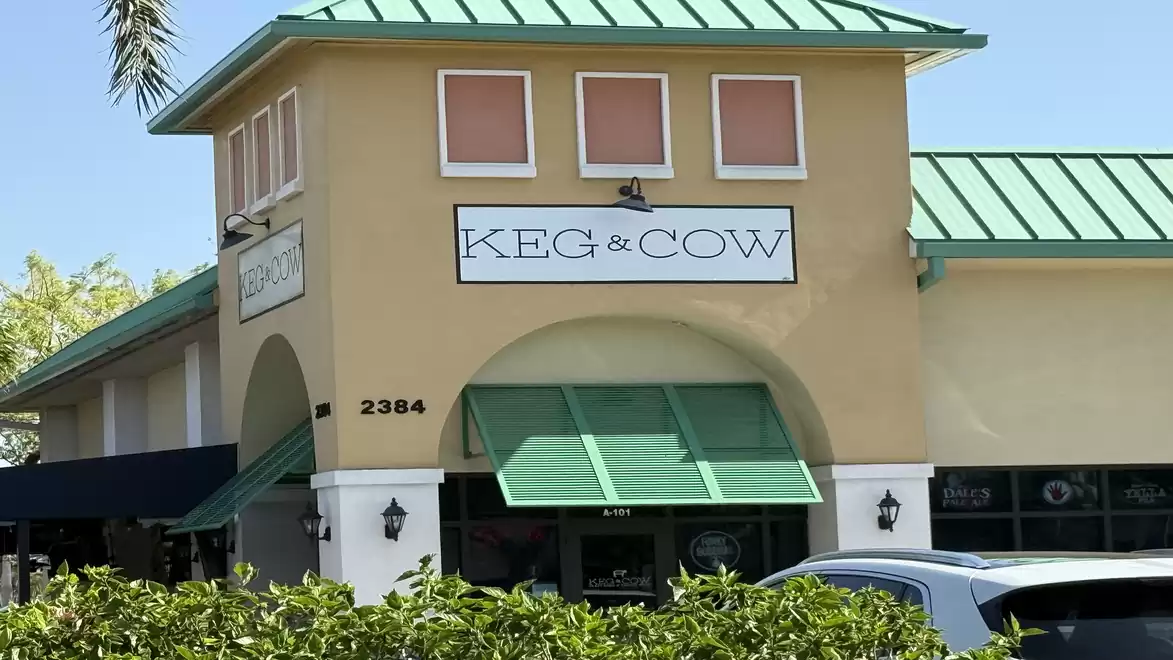 Exterior view of a restaurant named 'Keg & Cow' with a green roof on a sunny day.