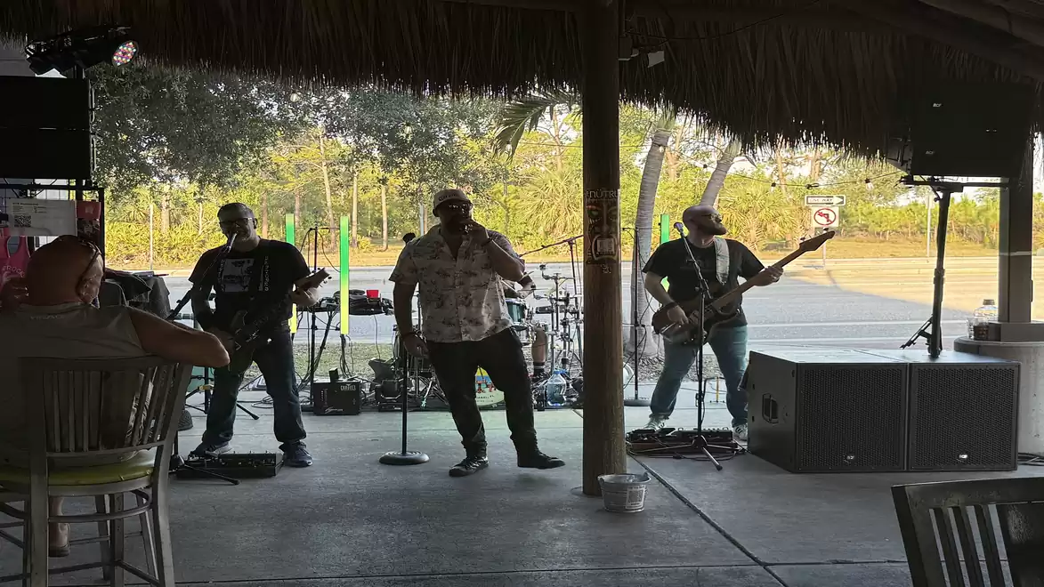 A band playing live music in a covered area with trees in the background.