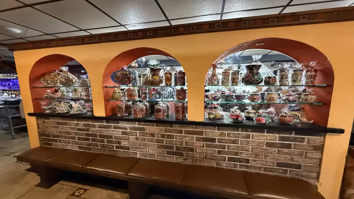 A wall with three large, illuminated shelves filled with various decorative vases and ceramics, including floral patterns.