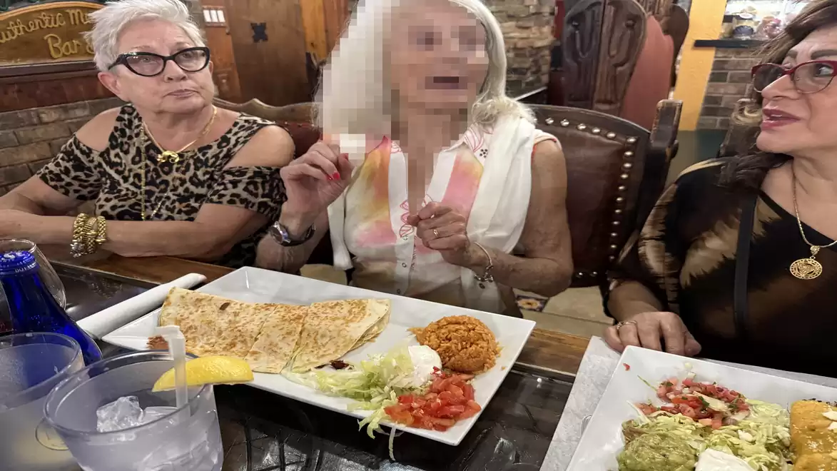 Three elderly women are sitting at a table in a restaurant enjoying a meal with various dishes.