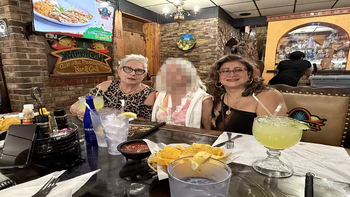 Three women sitting at a table with drinks and snacks in a cozy restaurant.