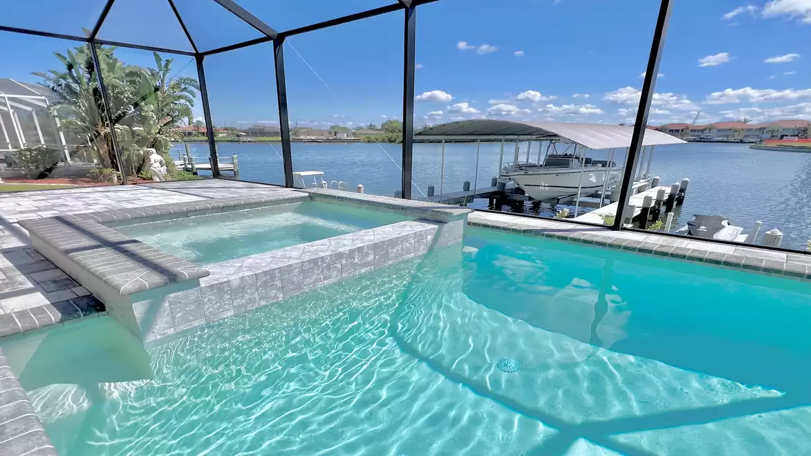 Villa Aldiana - Beautiful pool with covered outdoor area overlooking a tranquil lake on a sunny day.