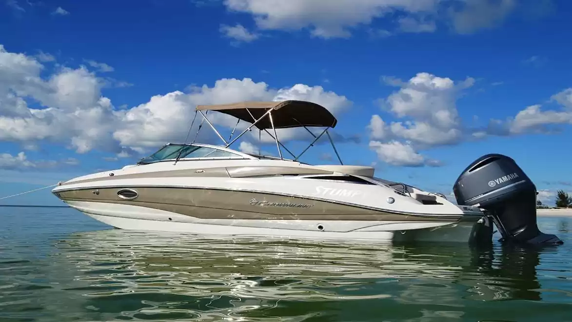 A white motorboat floats in clear water under a blue sky with clouds.