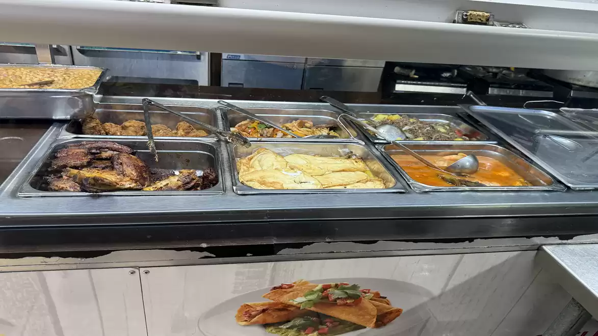 Buffet with various hot dishes, including meat, vegetables, sauces, and pasta.