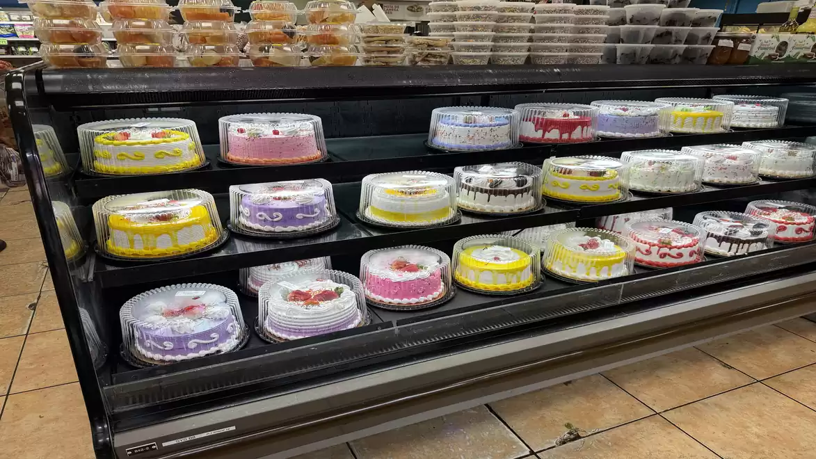 Display case with a variety of decorated cakes in a supermarket.