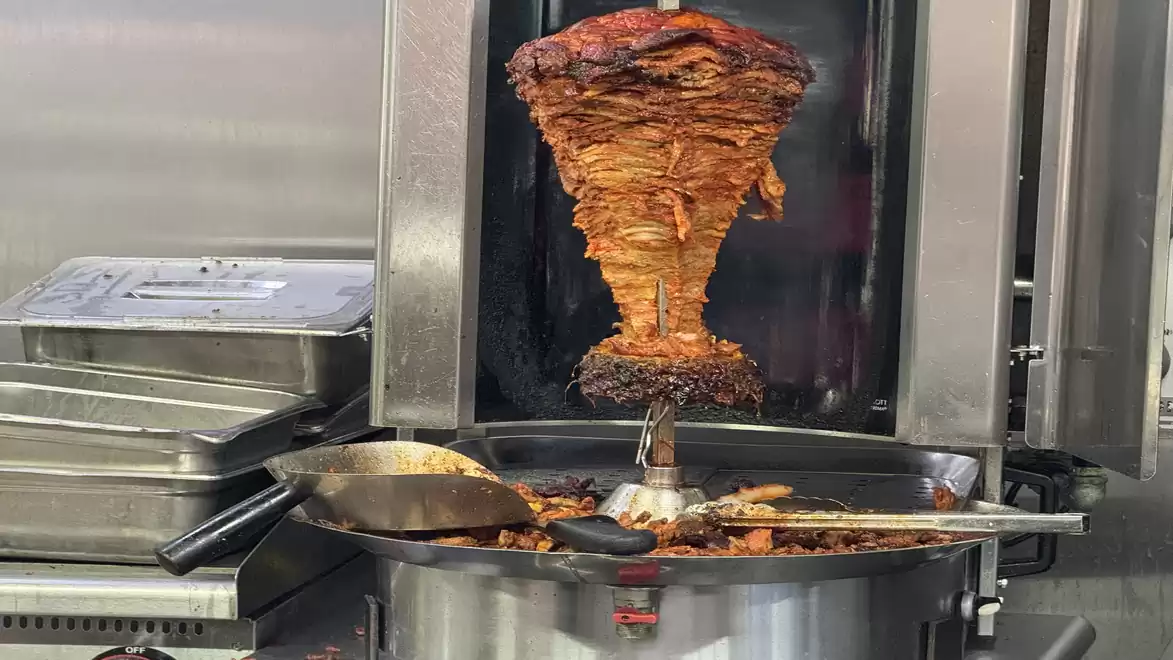 A rotating spit with grilled meat turning in a fast-food outlet, ready to be served.