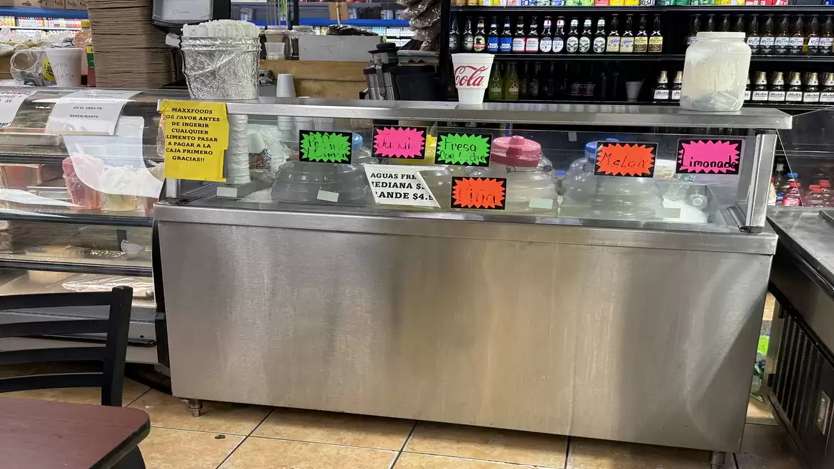 Interior view of a shop with a stainless steel display case featuring various colorful price tags and products.