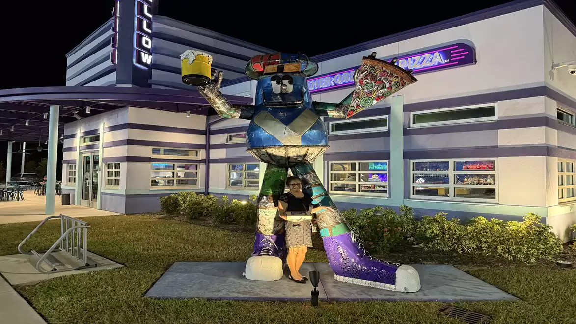 Colorfully lit statue of a robot in front of a building at night.
