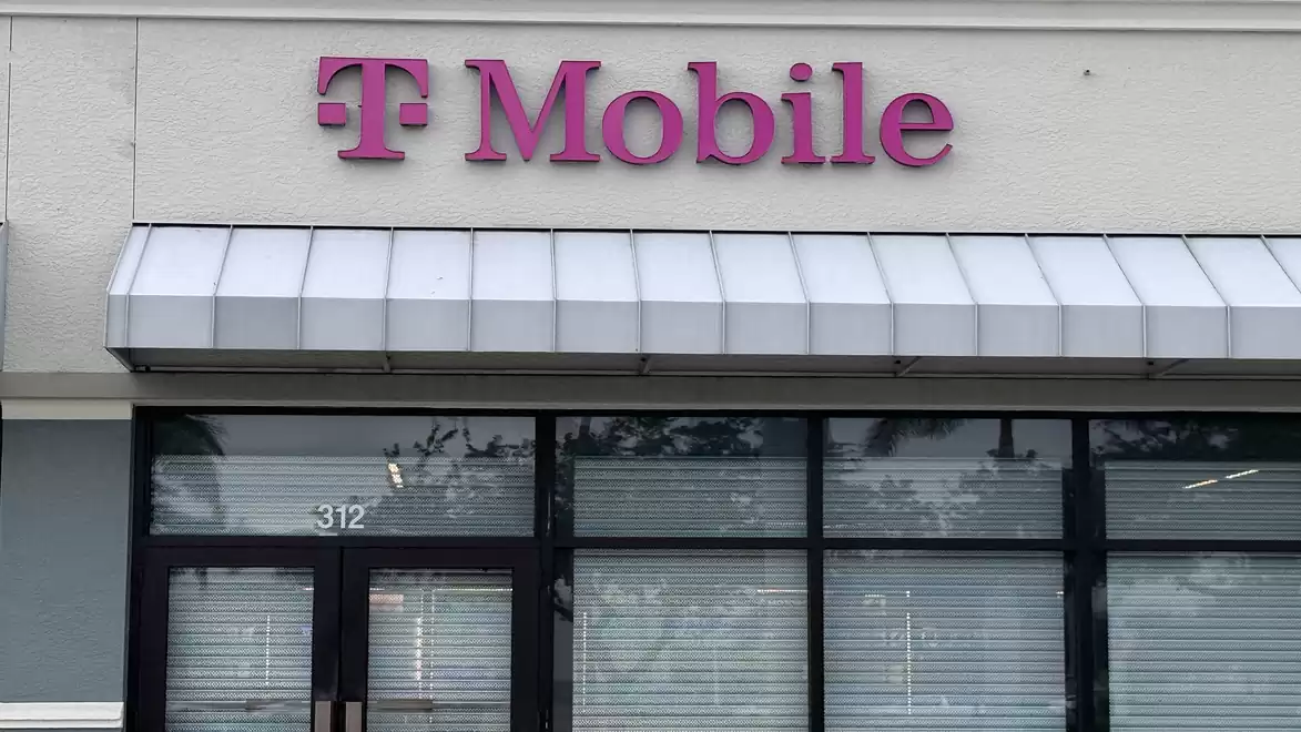 Storefront with pink 'T-Mobile' sign on white facade. Closed shutters and entrance doors visible.