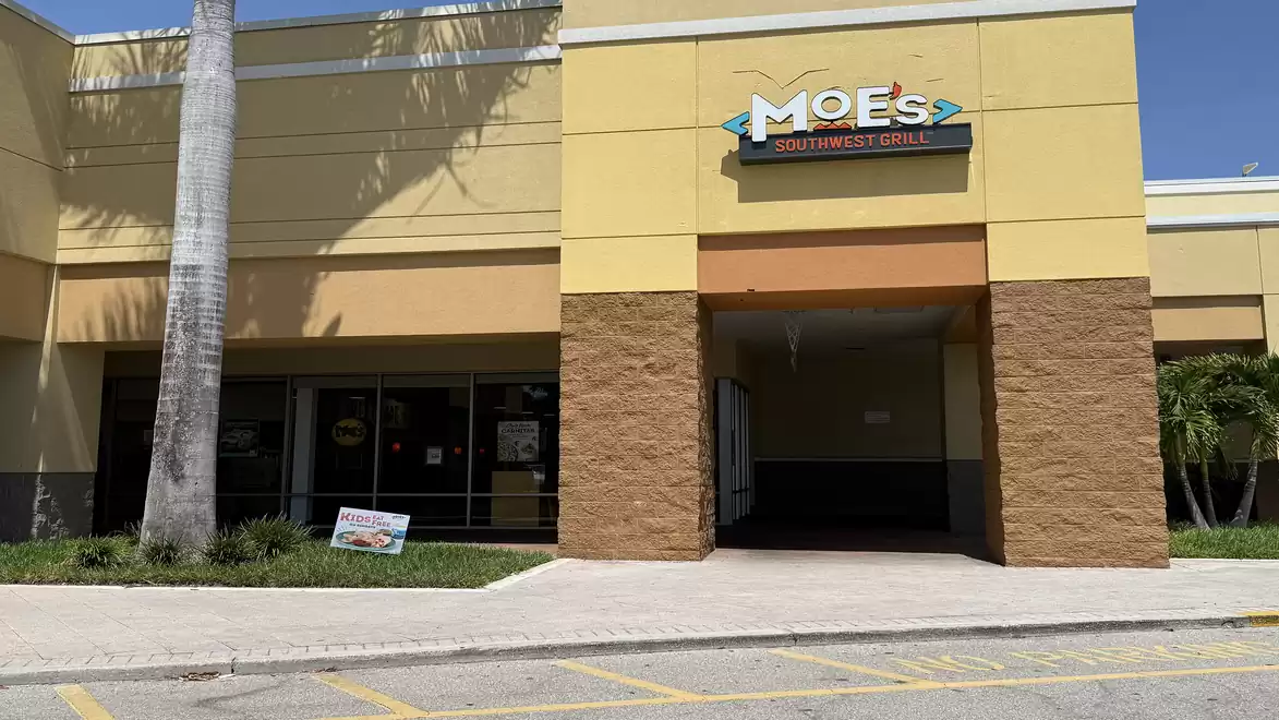 Entrance of a restaurant with yellow and brown walls, sign reading 'Moe's Southwestern Grill' above the door.