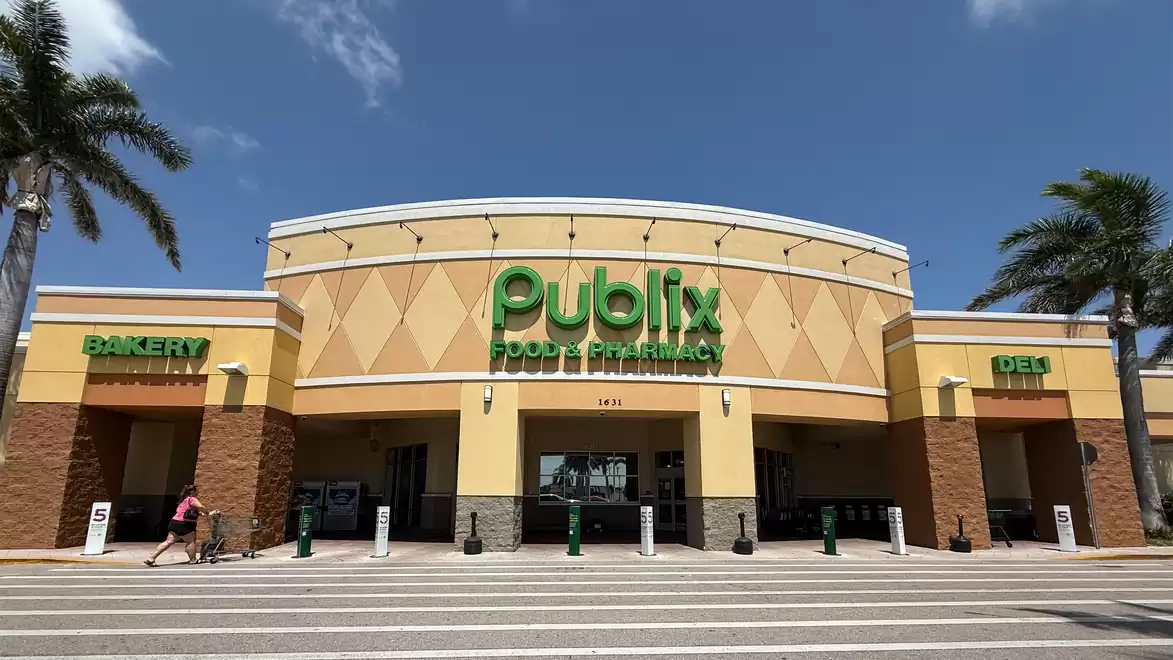Exterior view of a Publix supermarket with palm trees and a clear sky.