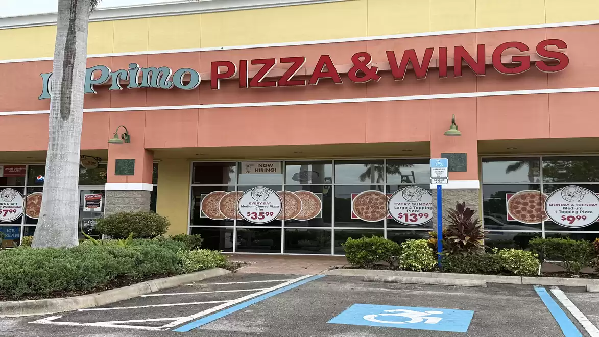Exterior view of a restaurant with the sign 'Pizza & Wings' in red letters above the entrance.