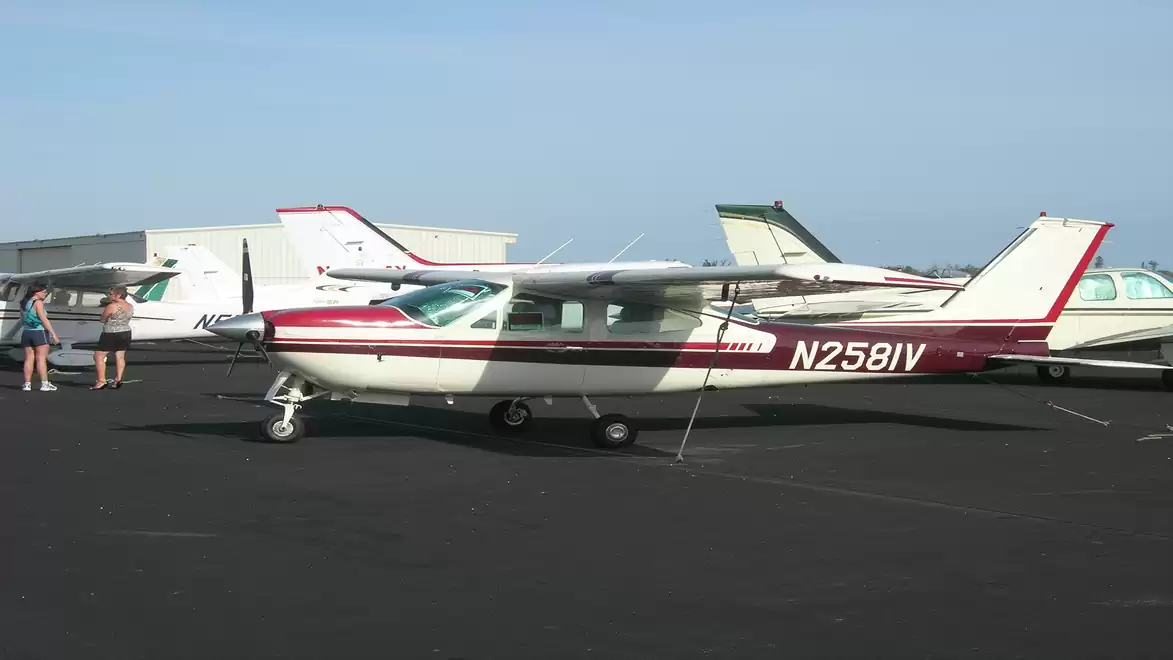 Small single-engine airplanes parked on an airfield under a clear sky.