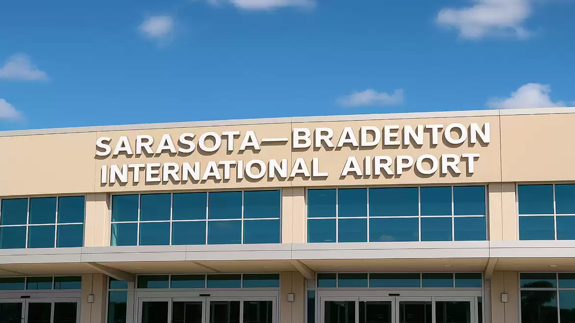 Entrance of Sarasota-Bradenton International Airport with large signage under a blue sky.