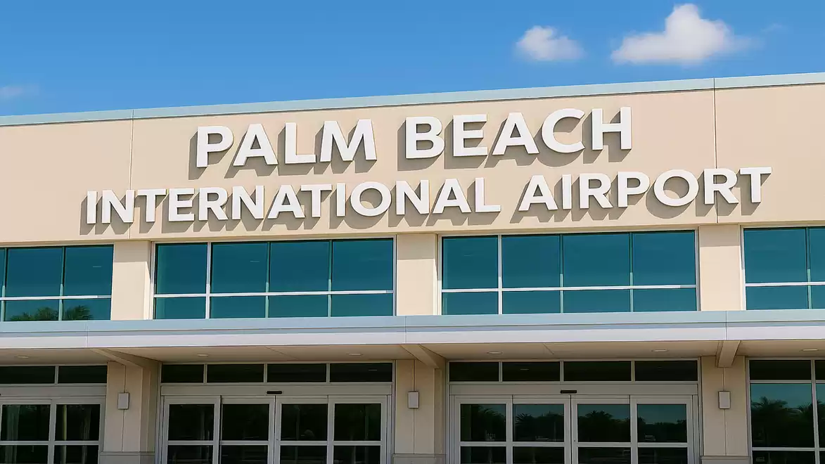 Entrance of Palm Beach International Airport with large windows and blue sky in the background.