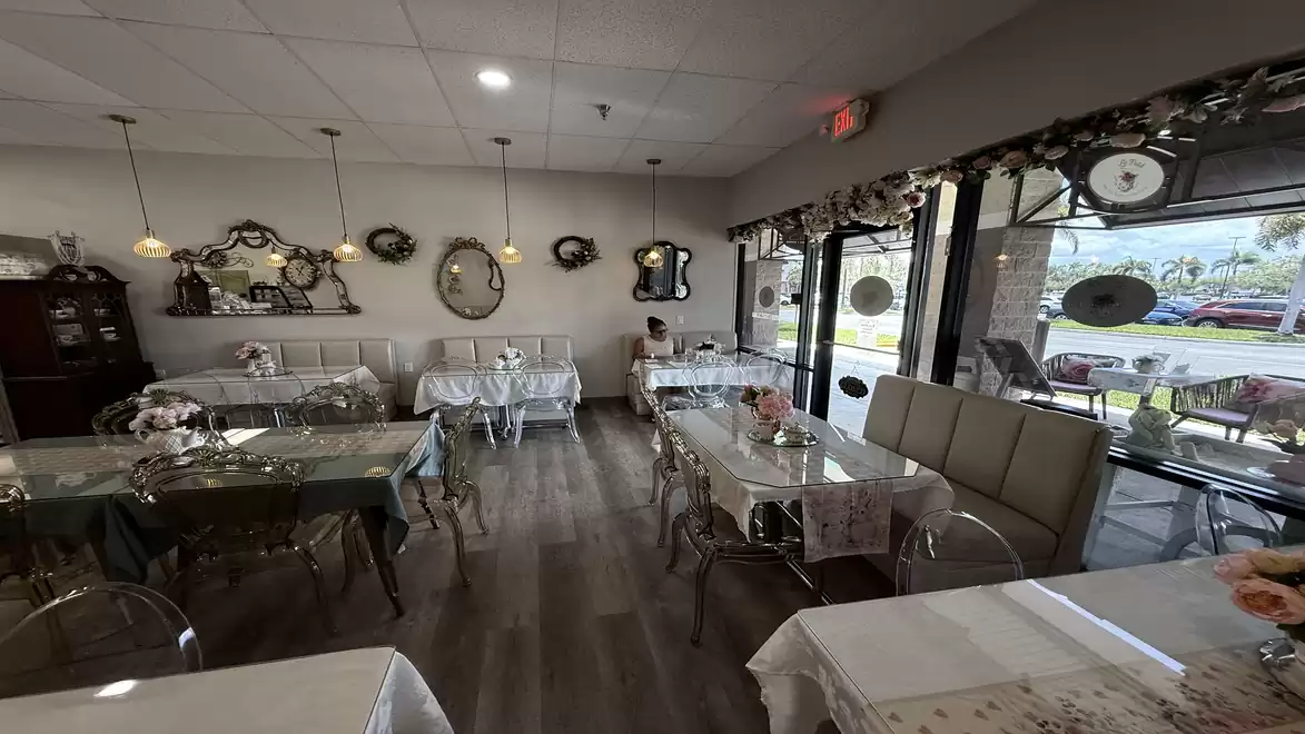 Cozy café with elegant decor and mirrors, daylight streaming through large windows.