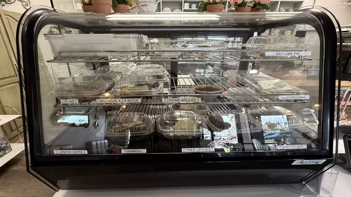 Empty bakery display case with vacant trays and price labels.