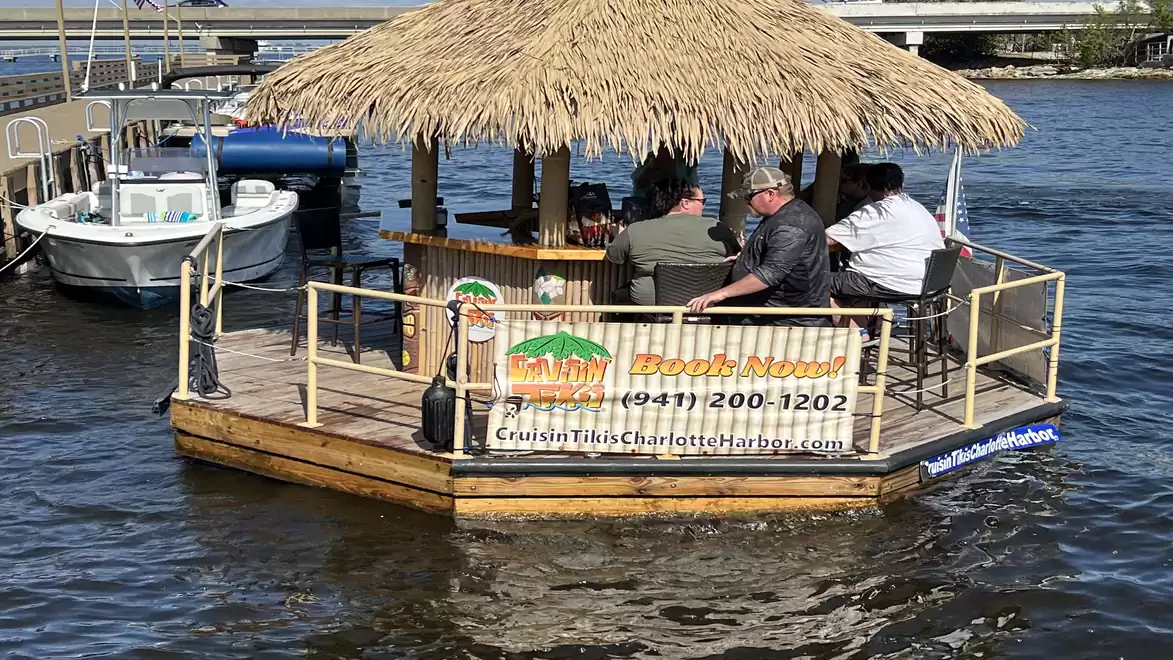 A floating raft with a thatched roof carrying people on the water.