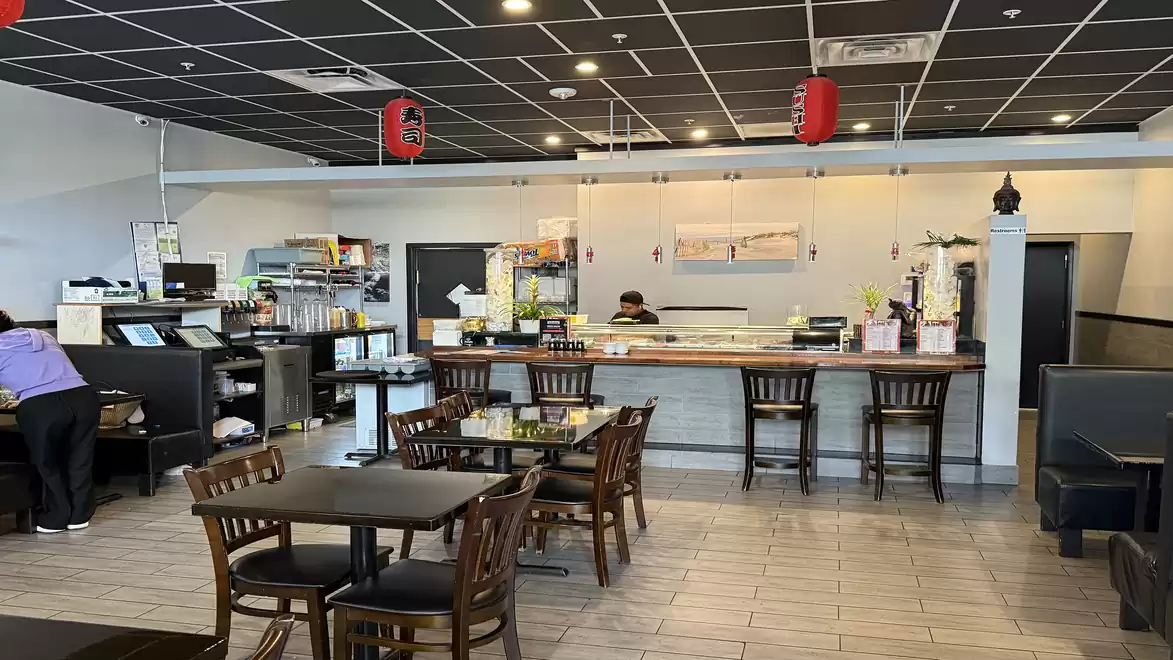 Modern Asian restaurant with dark wood furniture and a sushi counter in the background.