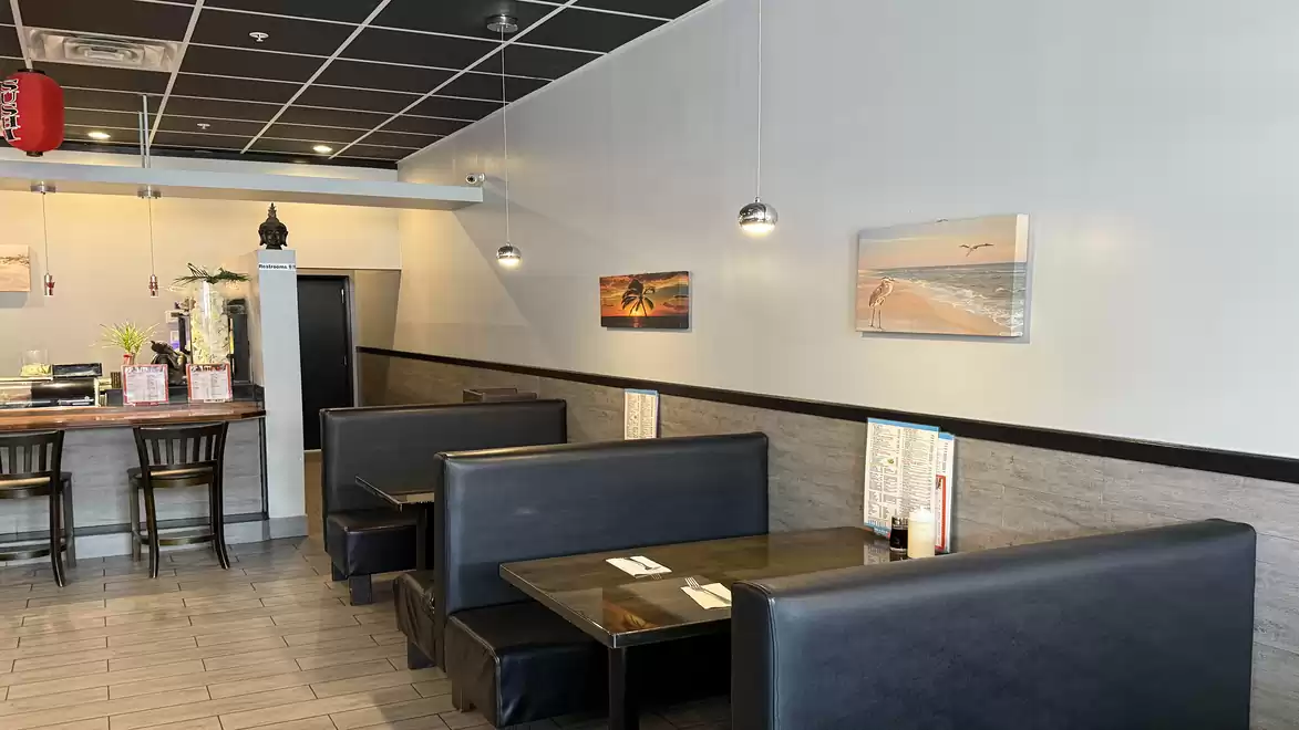 Interior view of a modern restaurant with stylish black booths and decorative pictures on the wall.