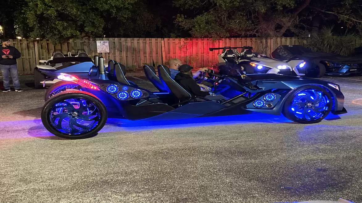 A three-wheeled vehicle illuminated with colorful lights at night.