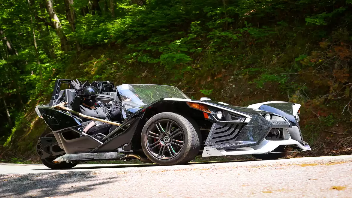 Three-wheeled vehicle parked on a road in the forest.
