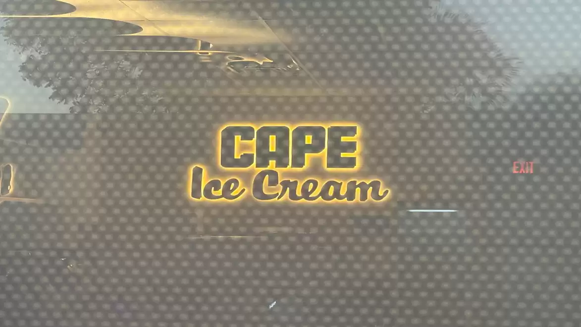 A glowing sign displaying 'Cape Ice Cream' against a blurred background.
