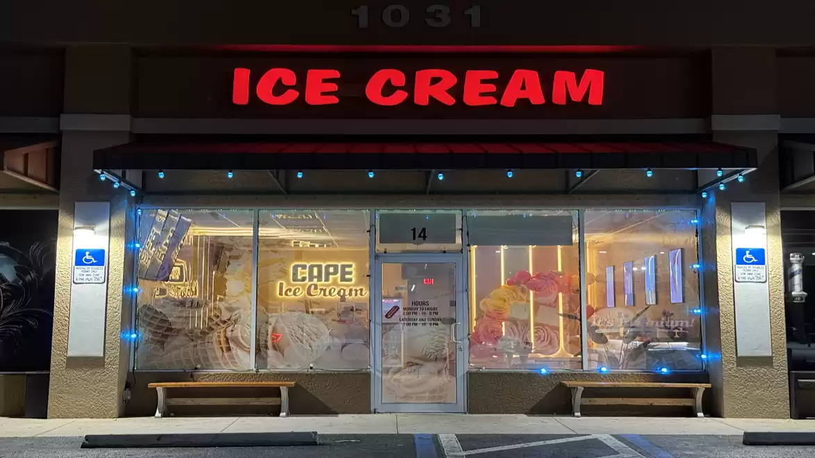 An ice cream shop with a bright red 'Ice Cream' sign above the entrance. The shopfront is decorated with blue and white lights.