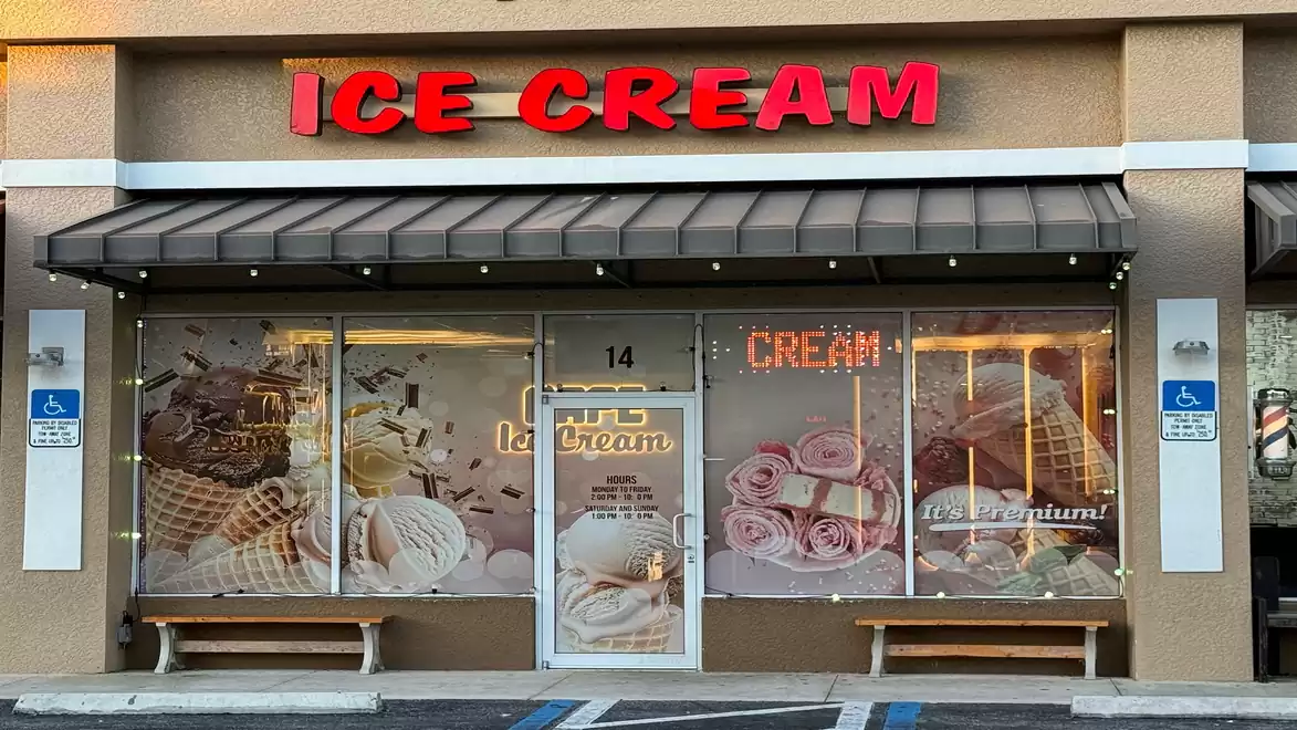 Exterior view of an ice cream shop with a bright red Ice Cream sign and a facade decorated with ice cream cone motifs.