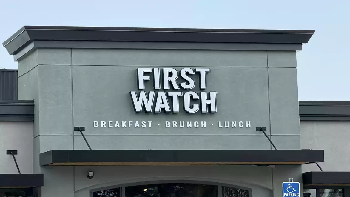 Exterior view of a restaurant named 'First Watch' offering breakfast, brunch, and lunch. A handicap parking sign is visible.