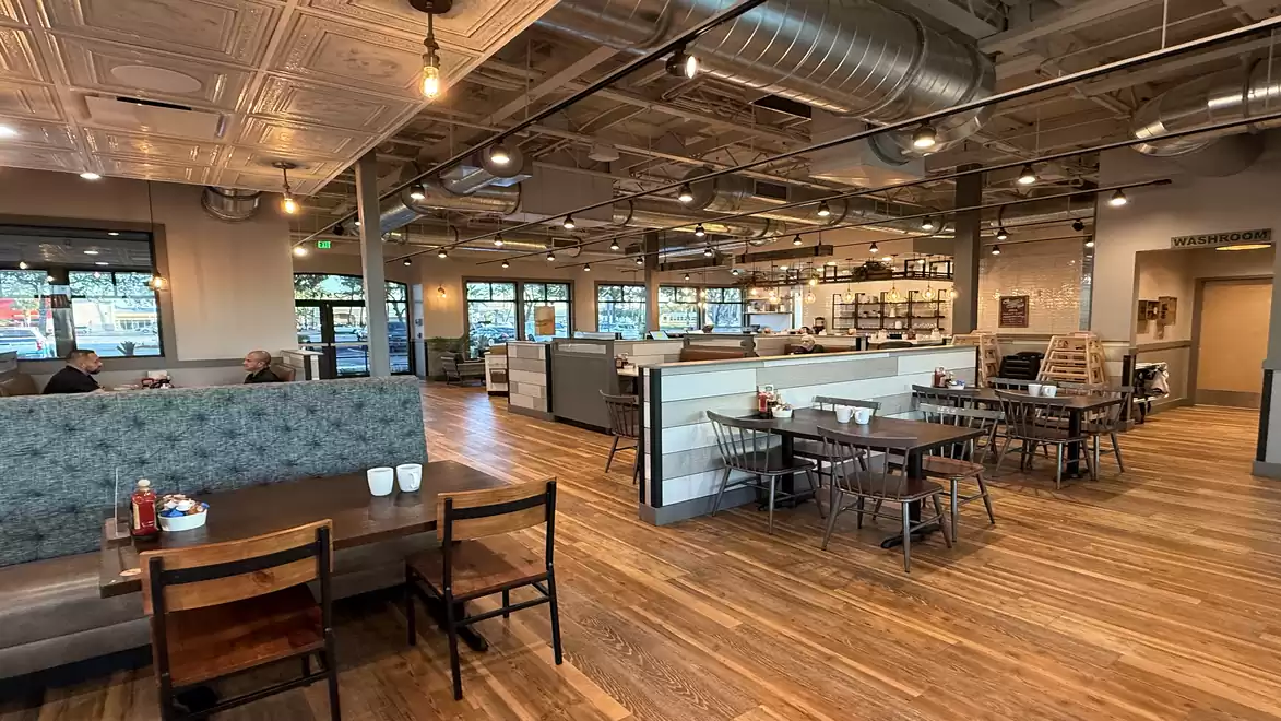 A modern café with wooden flooring, cozy seating, and industrial design.