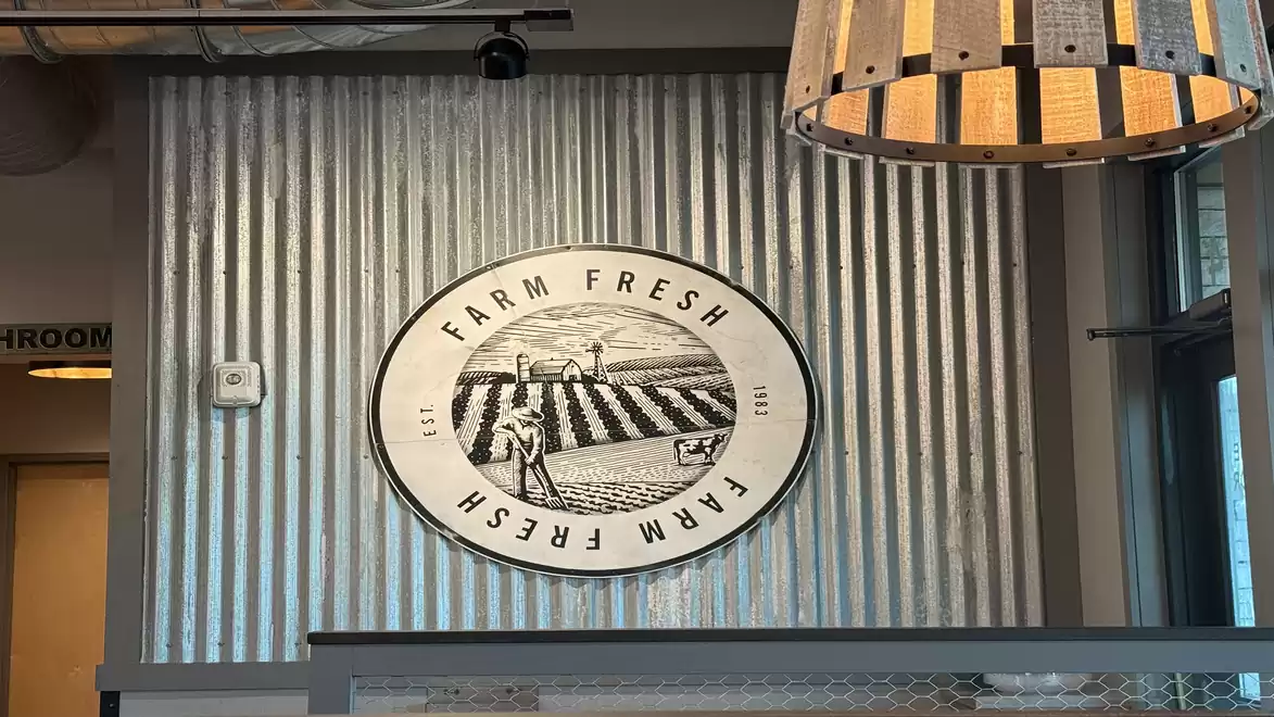 A sign reading 'Farm Fresh' hangs on a corrugated metal wall in an interior with modern decor.