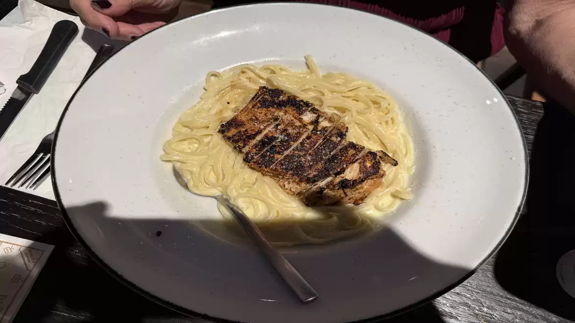 A plate of creamy pasta with grilled salmon served in a restaurant.