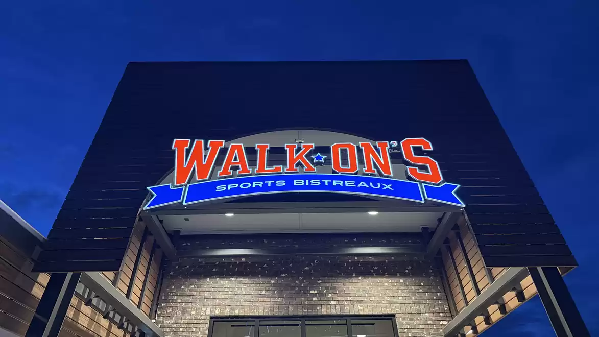Entrance to a Sports Bistreaux with illuminated Walk-On's sign and stylish architecture.