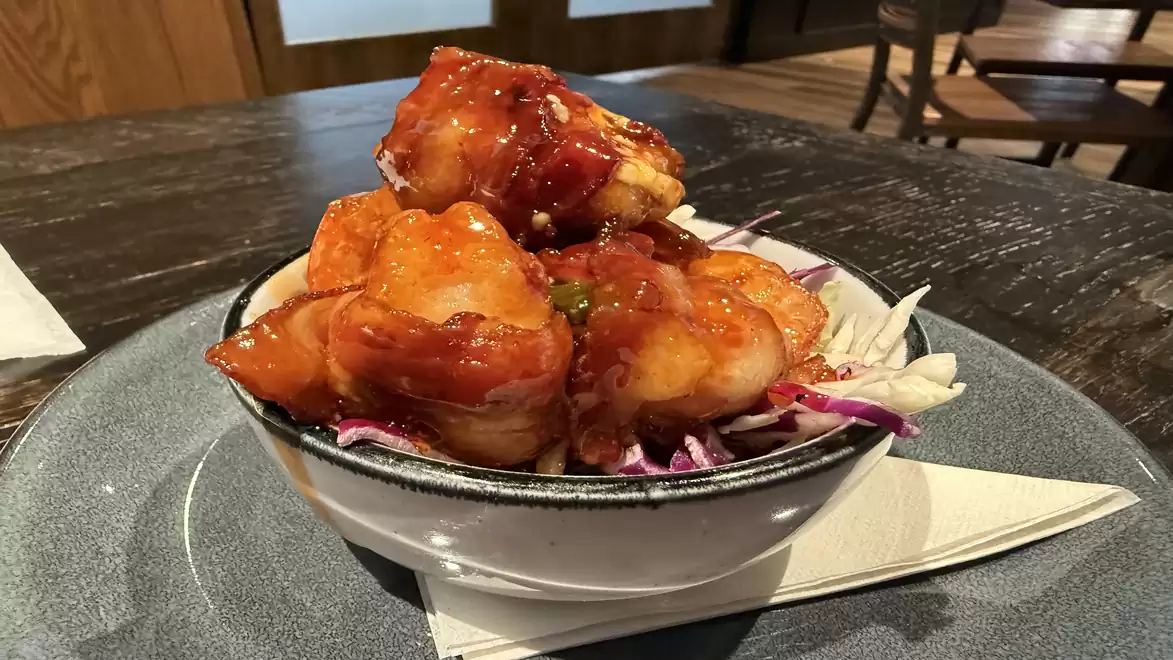 Close-up of a bowl with gambas in spicy sauce, served on a bed of coleslaw.