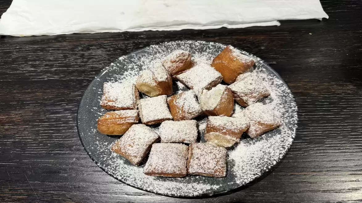 A plate of square pastries dusted with powdered sugar on a dark wooden table.