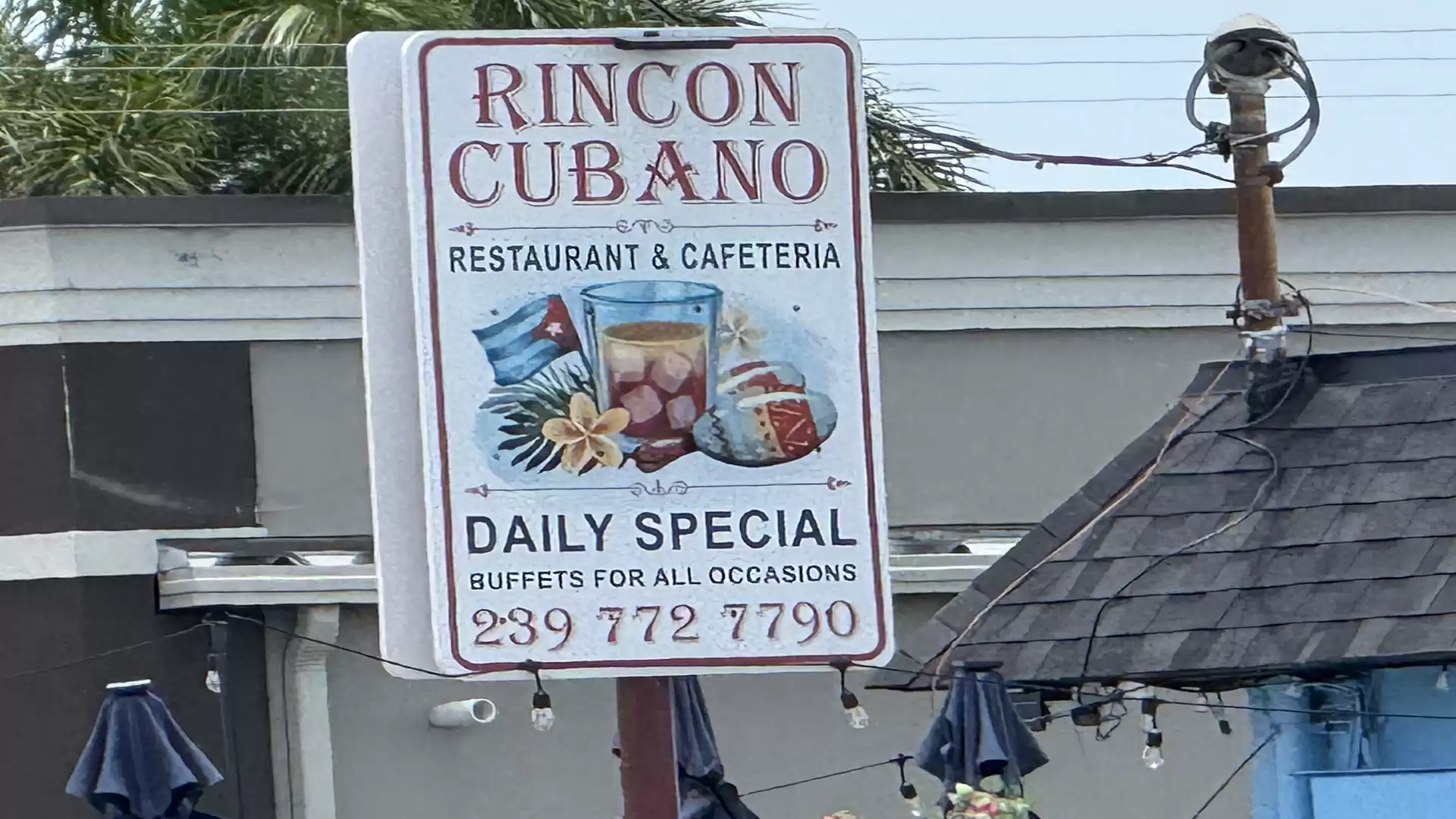 A sign reading 'Rincon Cubano', advertising a restaurant and cafeteria with a daily special and contact information.