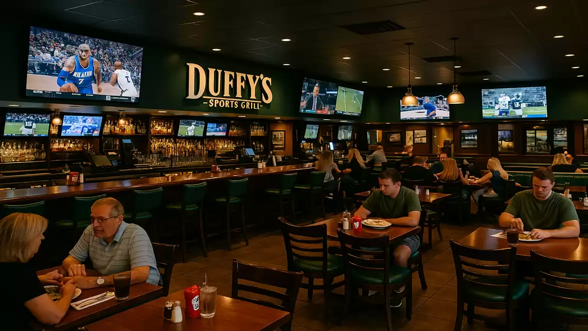 A busy sports restaurant with multiple TVs showing various sports events. Guests are seated at tables enjoying their meals.