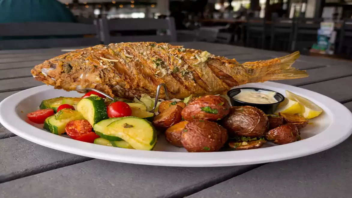 Grilled fish with vegetables and potatoes served on a plate in a restaurant.
