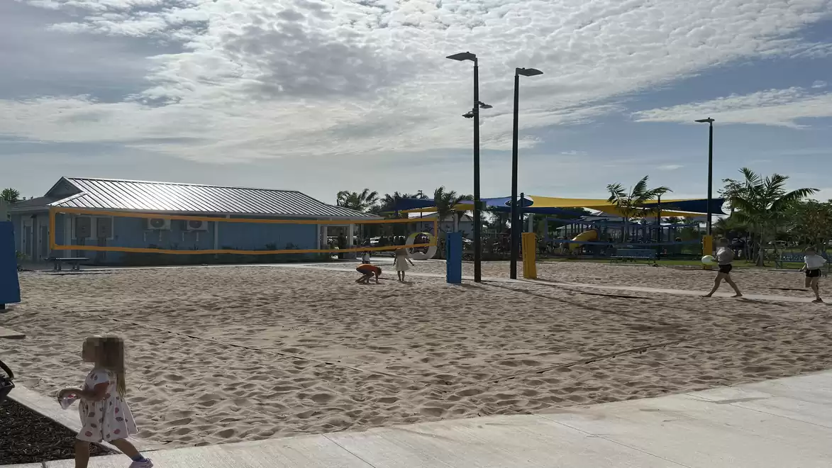 Beach area with huts and palm trees, people enjoying the sunny weather.