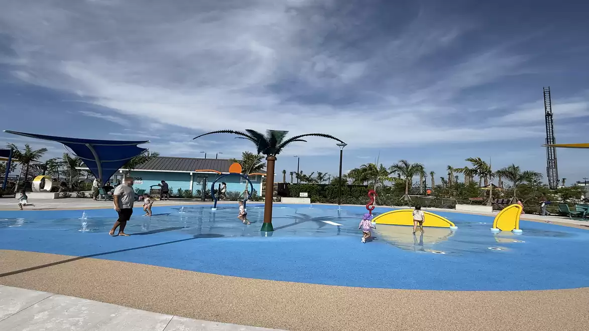 A playground in Jaycee Park, Cape Coral, featuring water play areas, palm trees, and children playing in the water.