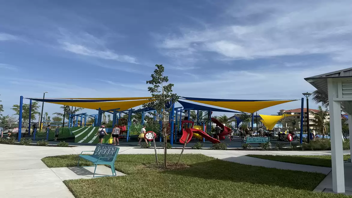 A colorful playground in Jaycee Park, Cape Coral with play equipment and sunshades.