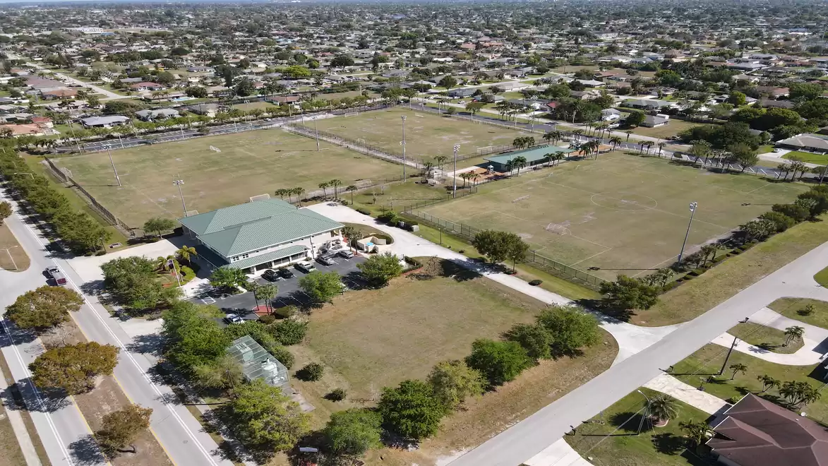 Aerial view of a large sports complex with several playing fields surrounded by a residential neighborhood.