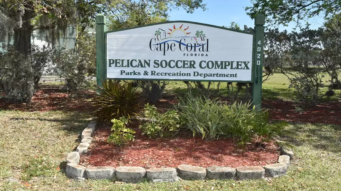 Sign of Pelican Soccer Complex in Cape Coral, Florida, surrounded by plants and stone edging.