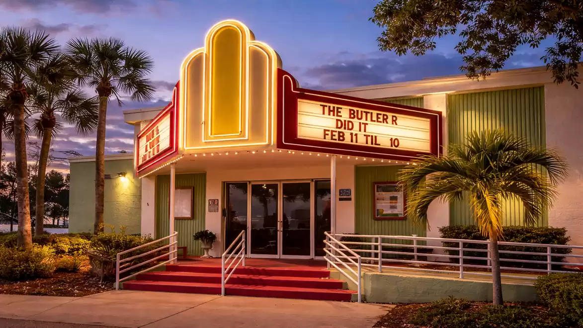 A vintage theater with a glowing neon sign displaying the play 'The Butler Did It'.