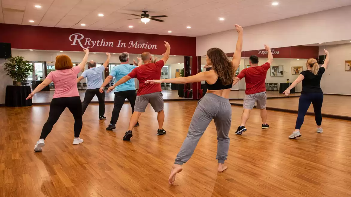 A group of people dancing in a dance studio with wooden floor and mirrored wall.