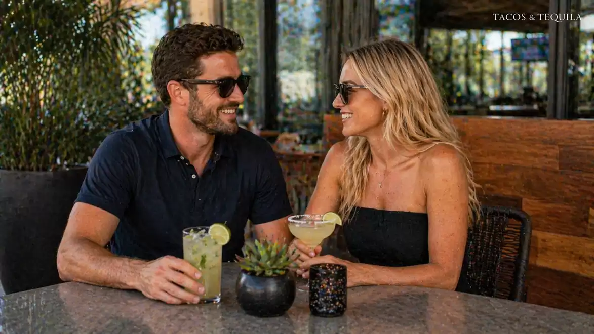 A smiling couple sits at a table enjoying cocktails at Tacos & Tequila.