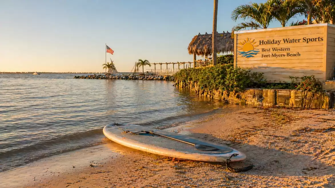 Beach at Fort Myers Beach with a paddleboard on the sand and a sign for Holiday Water Sports.